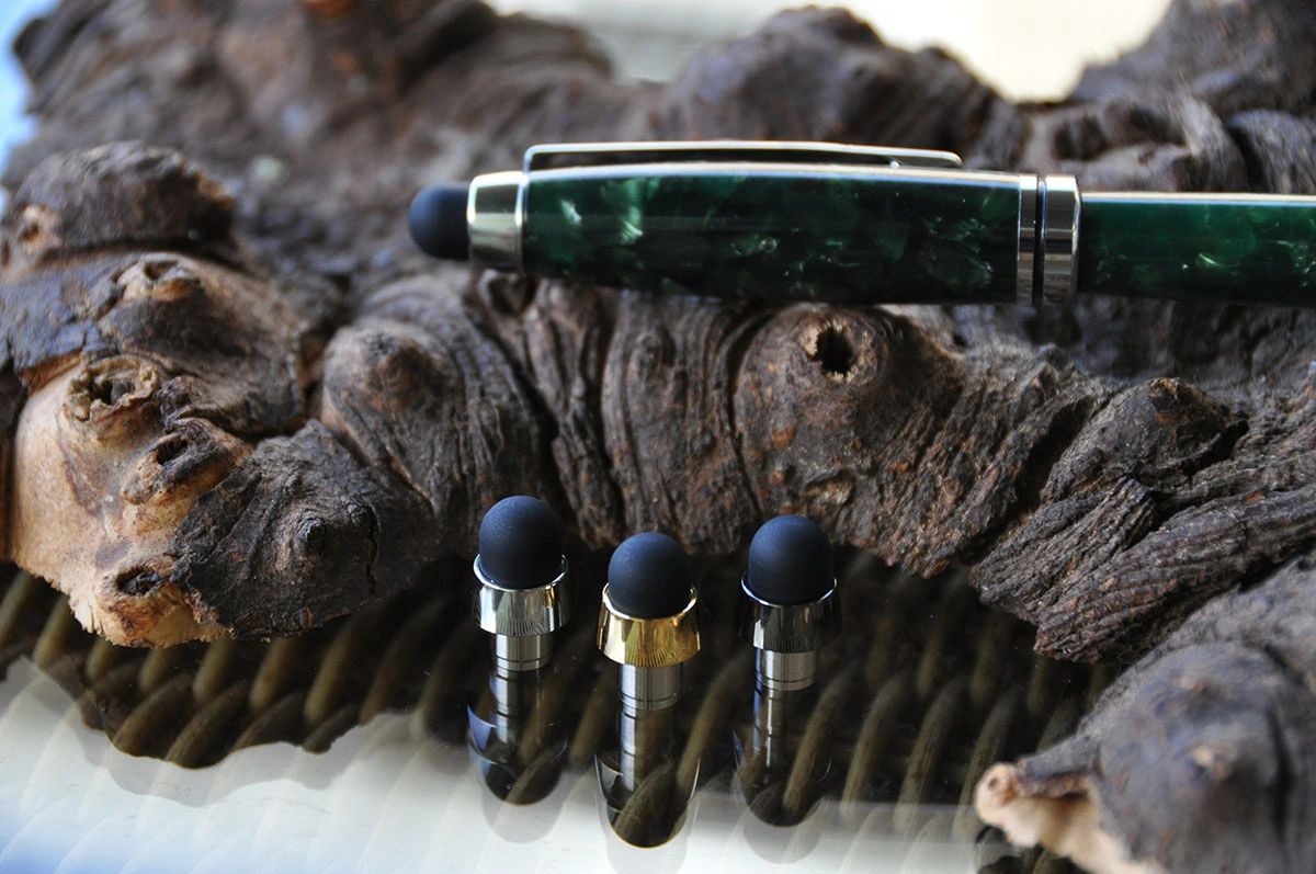 Green pen and styluses on wooden background.