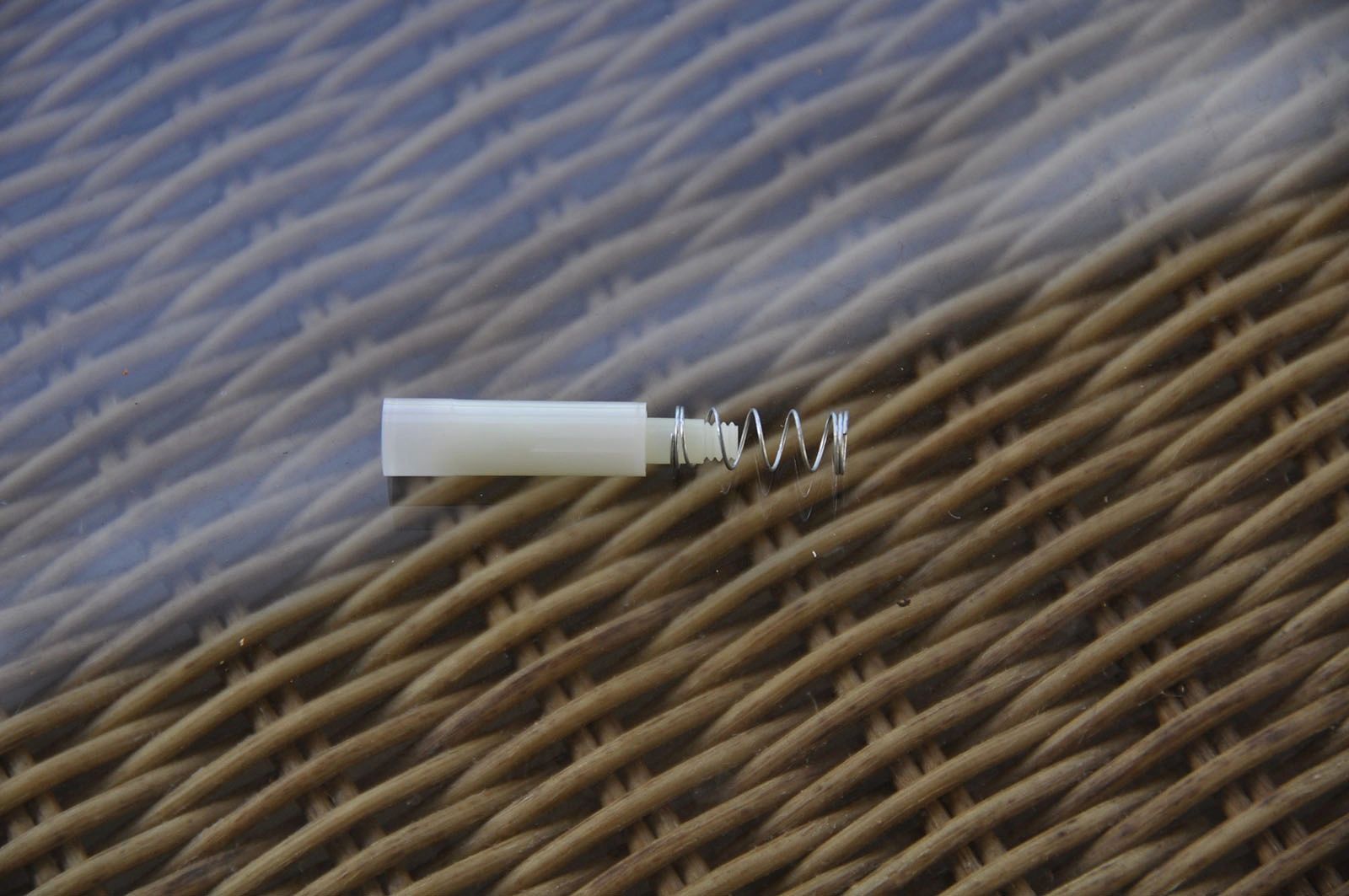 Small tube and spring on wicker texture.